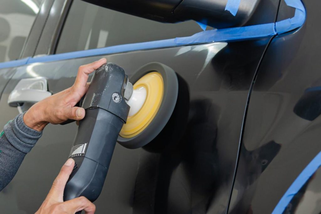 serviços de estética automotiva: homem limpando o carro 