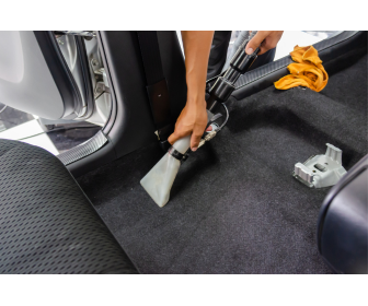 Processo inicial de limpeza de carpete automotivo com aspirador de pó.